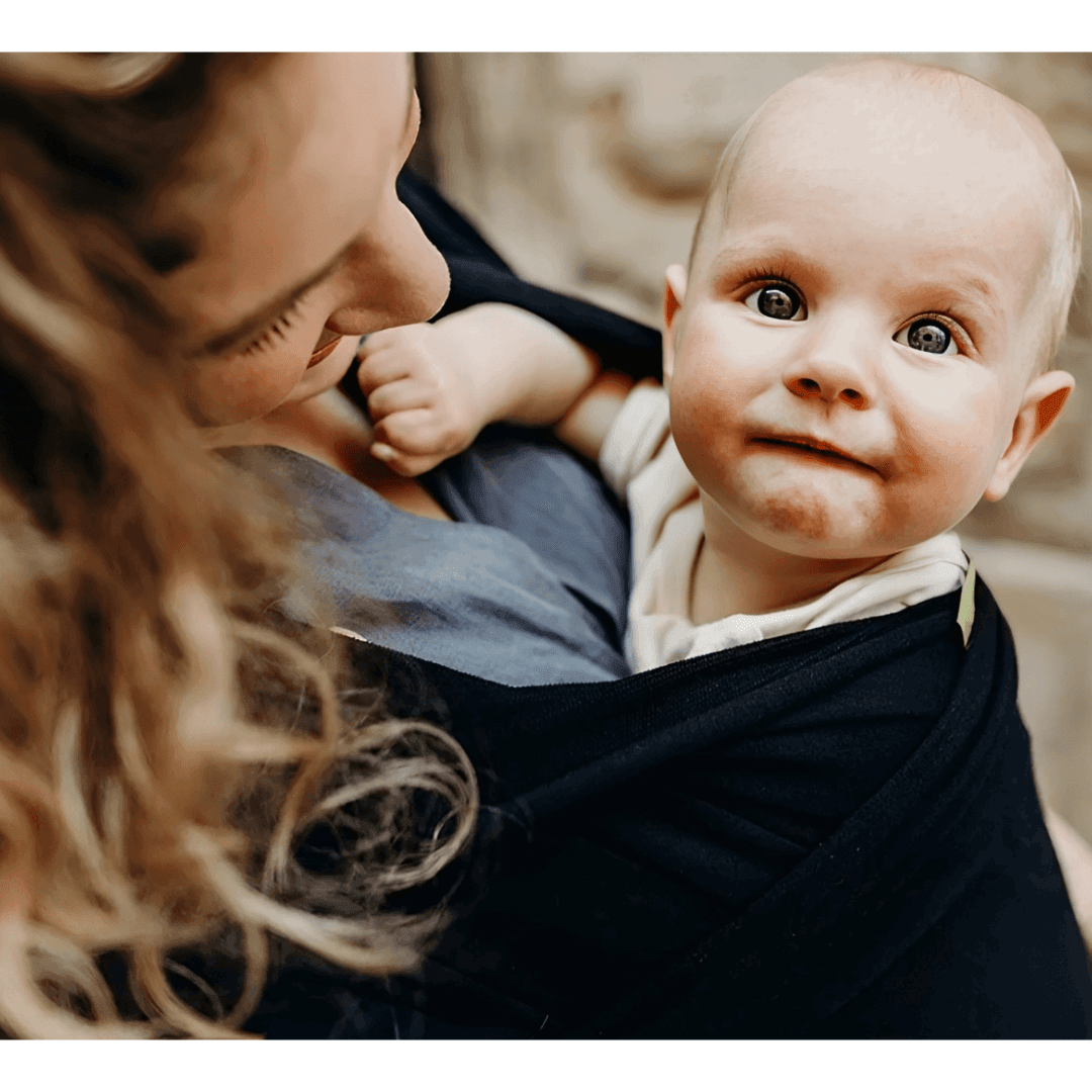 woman with a baby in a black baby wrap carrier - un bébé dans un écharpe pour bébé noir et une femme - VLF Shop