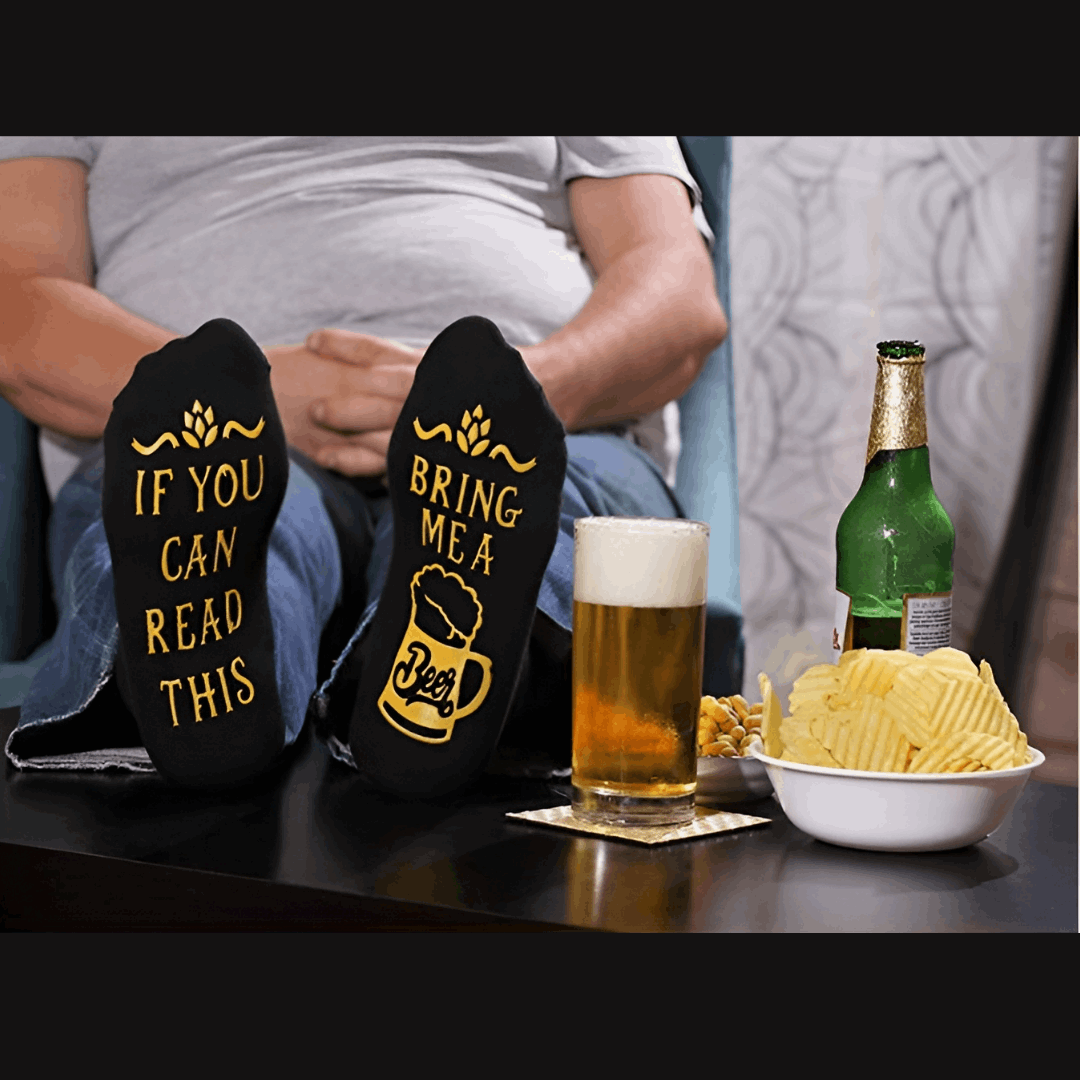 man wearing funny black beer socks with his feet on the table - un homme portant des bas amusant avec logo de bière les pied posé sur la table